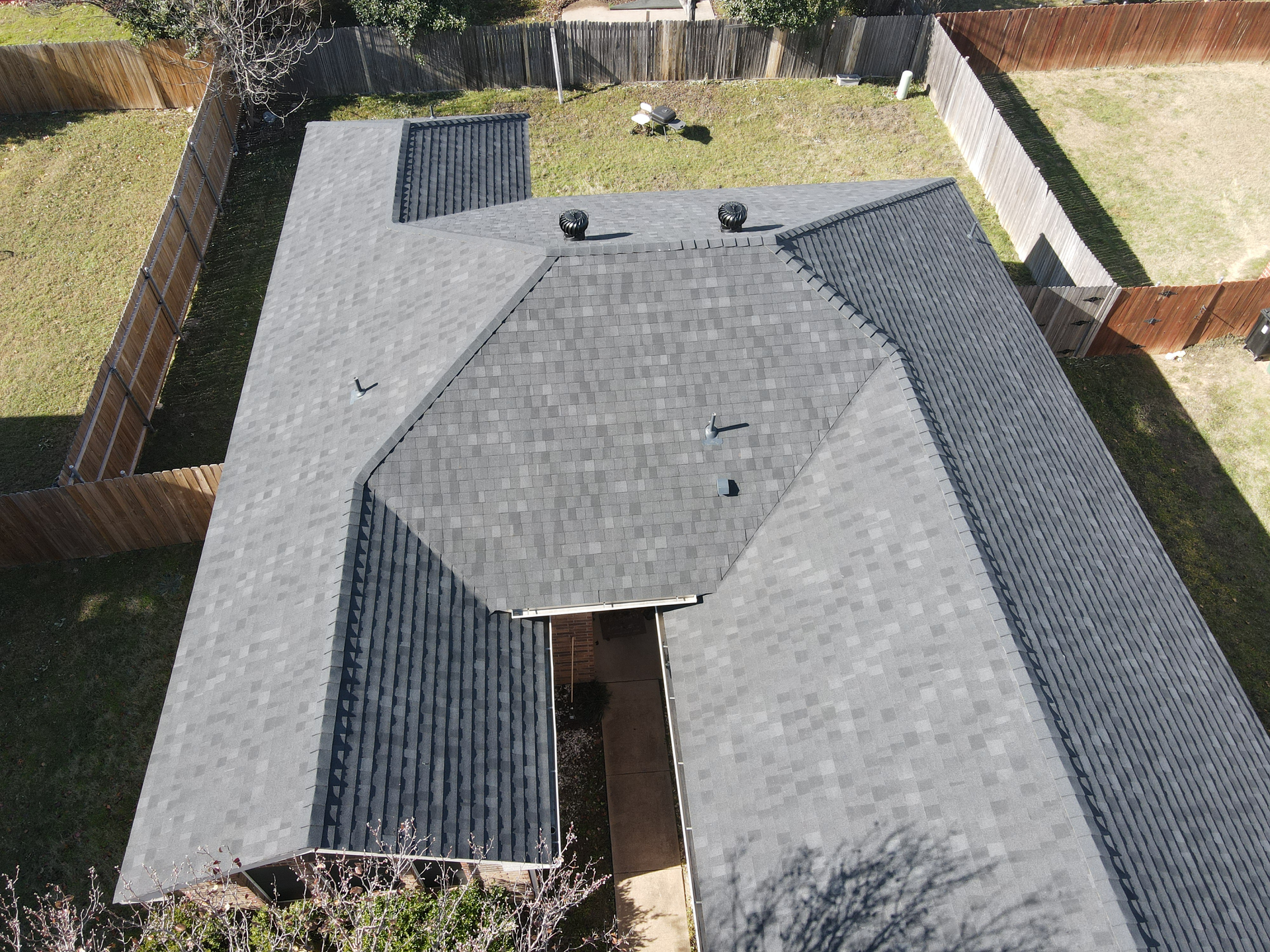 An aerial view of a roof of a house with a fence in the background.