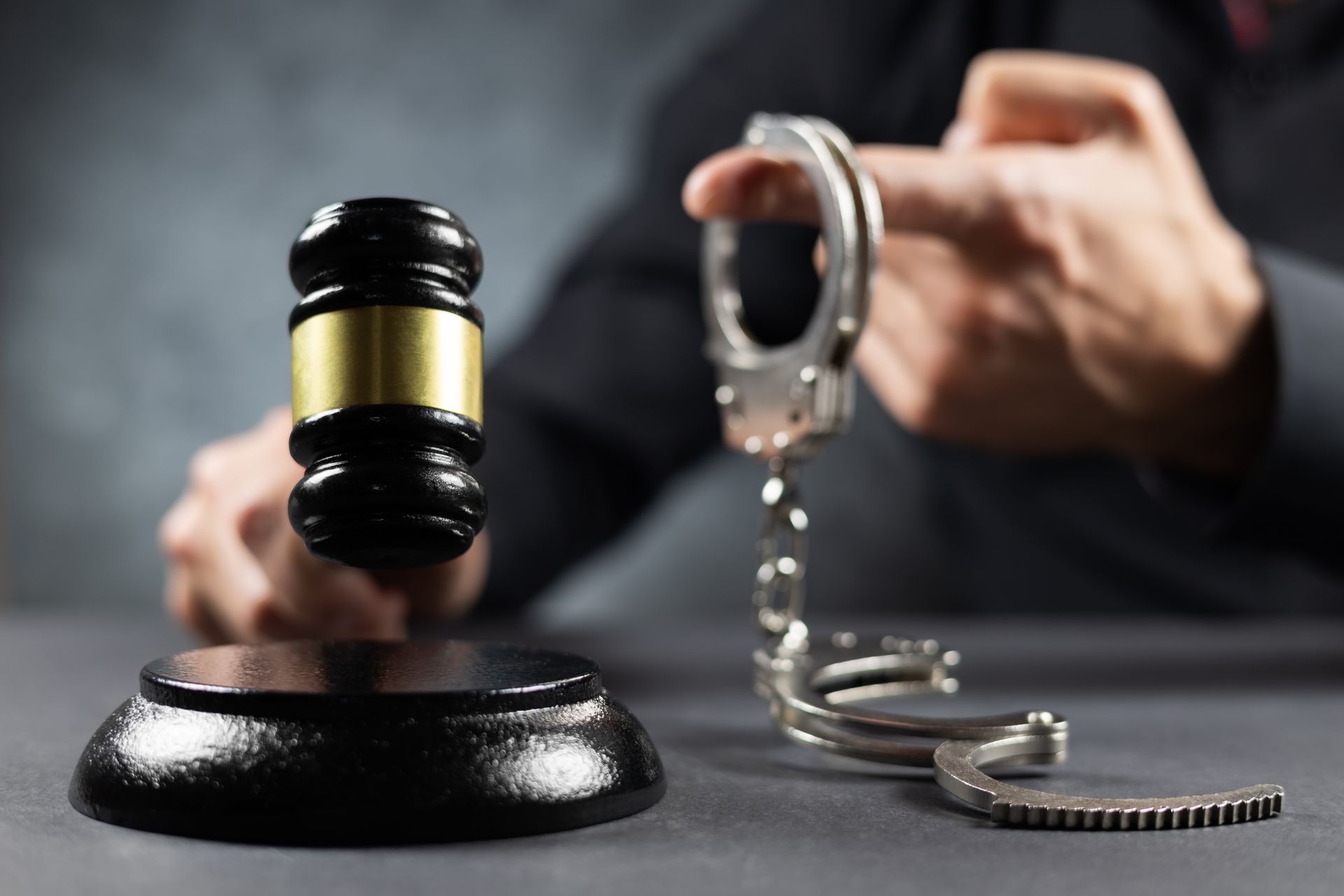 Judge's gavel held with handcuffs on a dark background. Judge's gavel held with handcuffs on a dark background.
