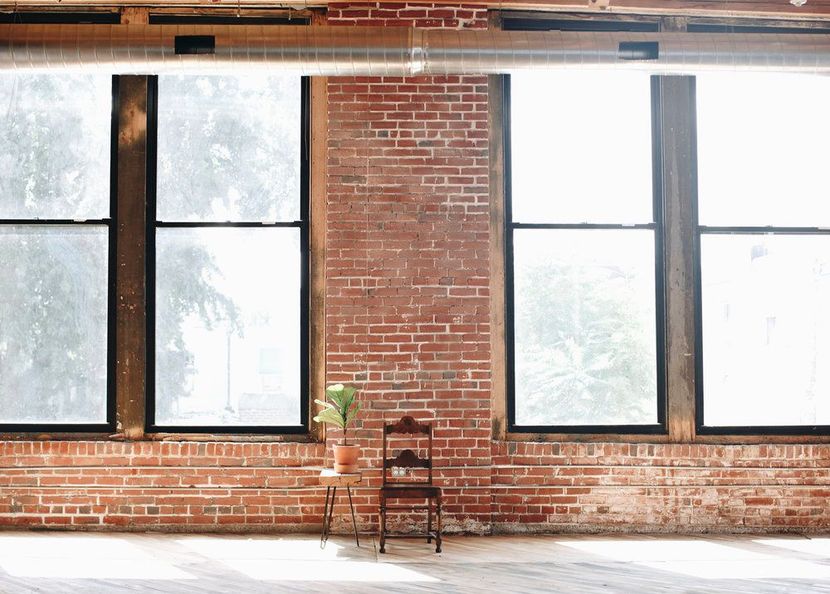 a chair is sitting in front of a brick wall with lots of windows .