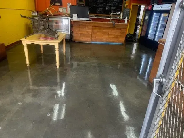 Interior of a commercial space with a polished concrete floor, a table, and a counter. 
