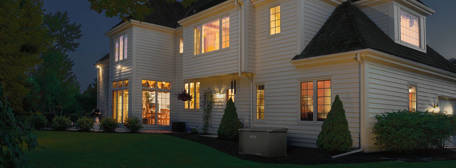 vue extérieure d'une maison beige en soirée avec éclairage intérieur allumé