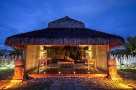 Uma pequena cabana com telhado de palha é iluminada à noite.