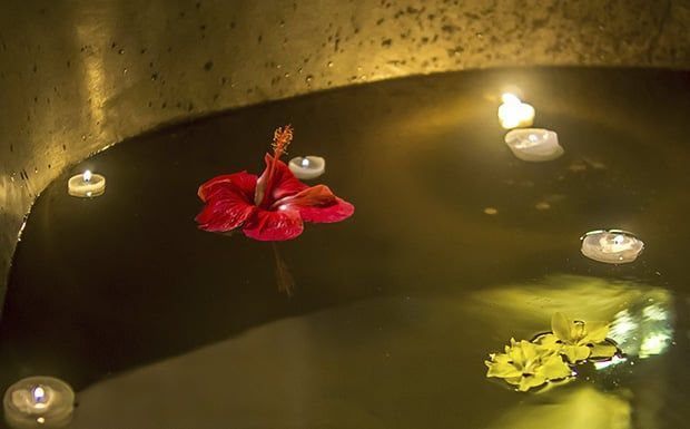 Uma banheira com velas e flores flutuando nela.