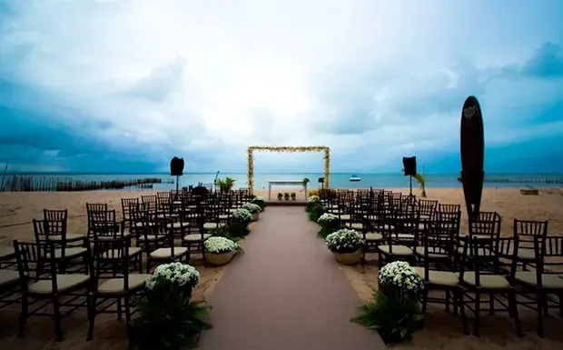 Uma cerimônia de casamento está acontecendo na praia.