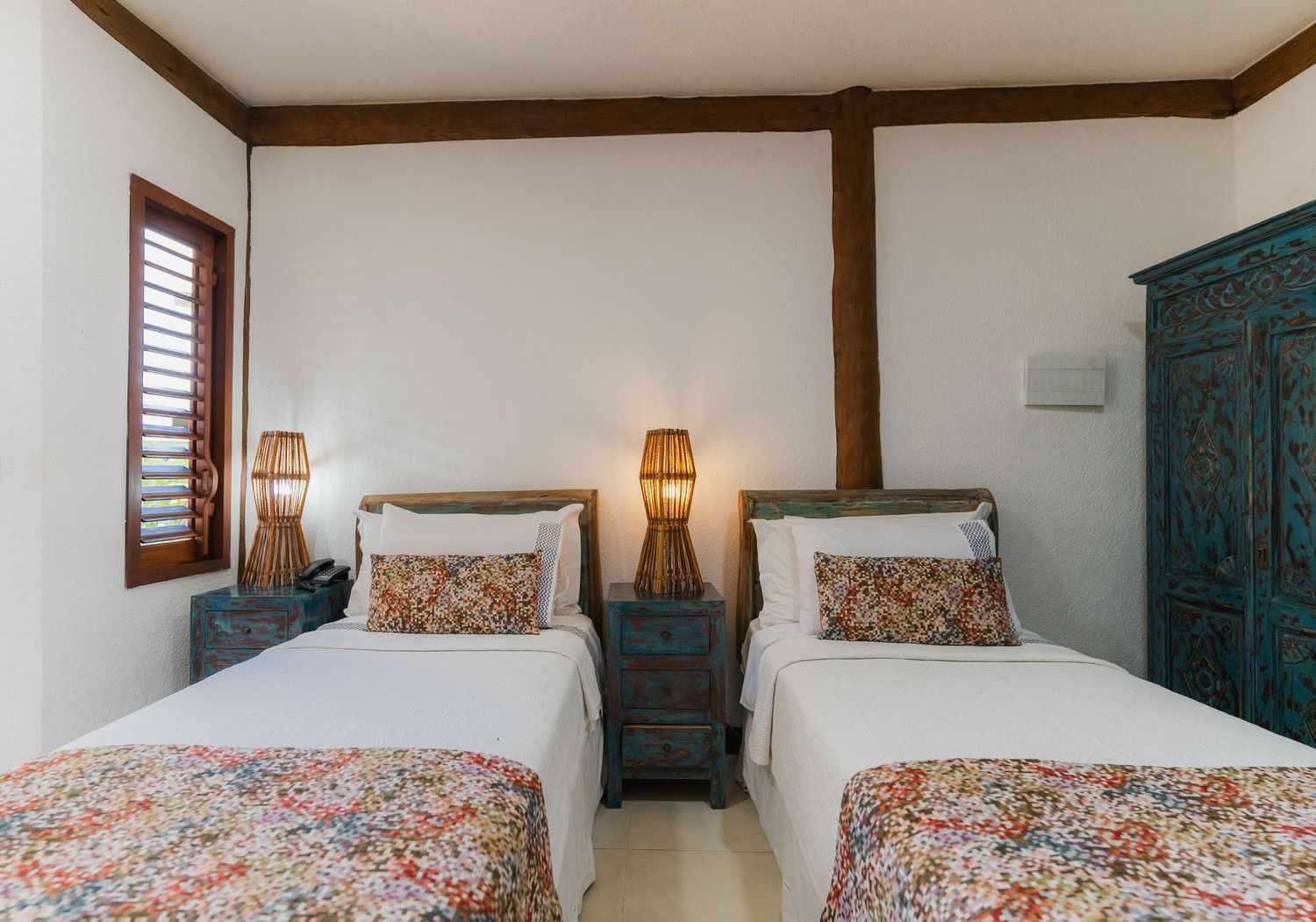 Um quarto com duas camas de solteiro e um guarda-roupa azul.