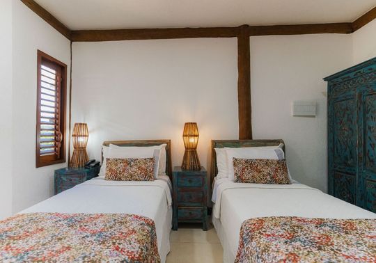 Um quarto com duas camas de solteiro e um guarda-roupa azul.