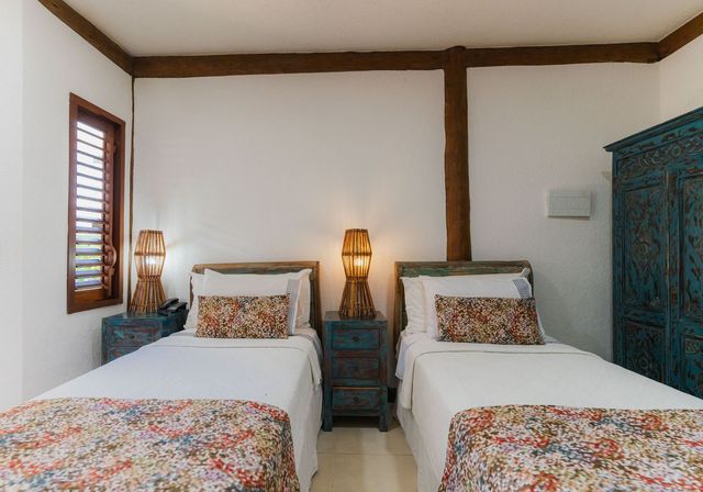 Um quarto com duas camas de solteiro e um guarda-roupa azul.