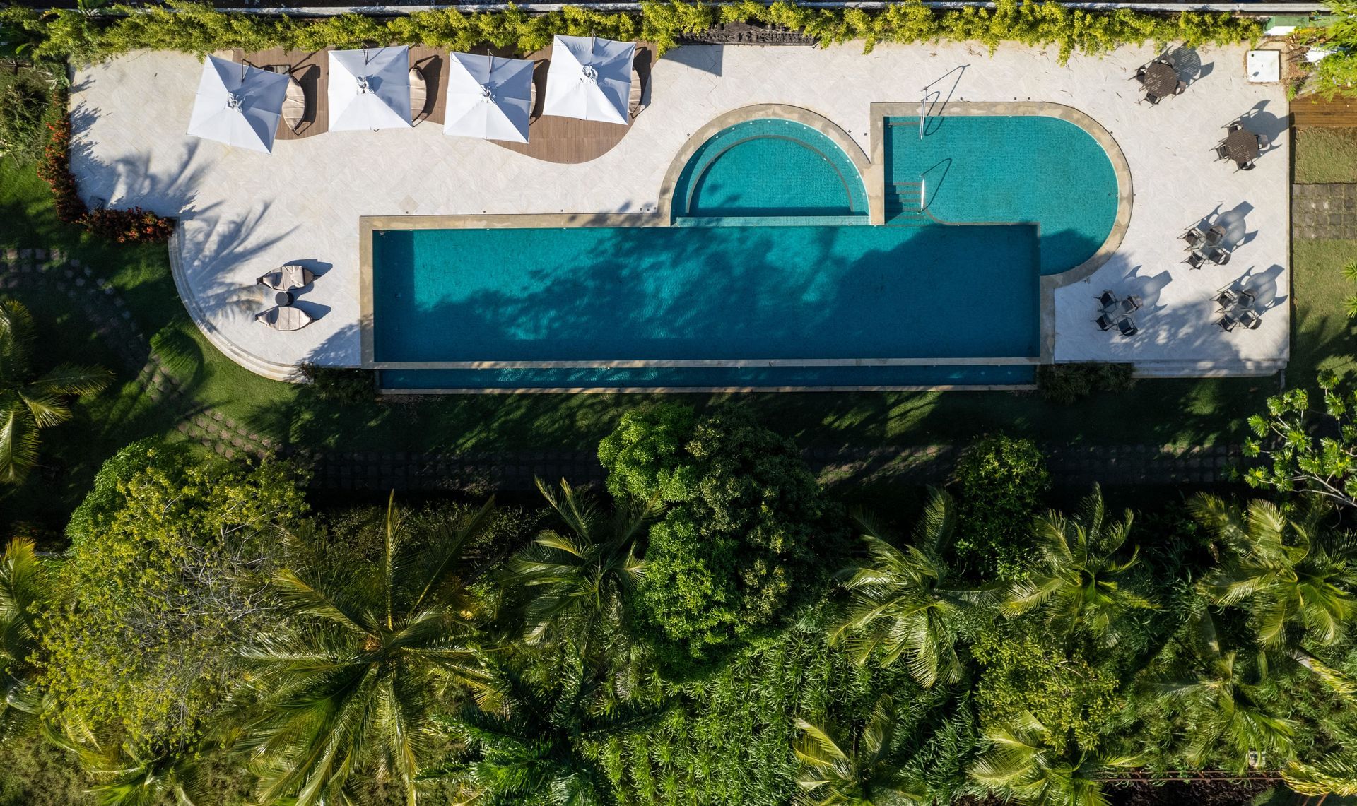 Uma vista aérea de uma grande piscina cercada por palmeiras