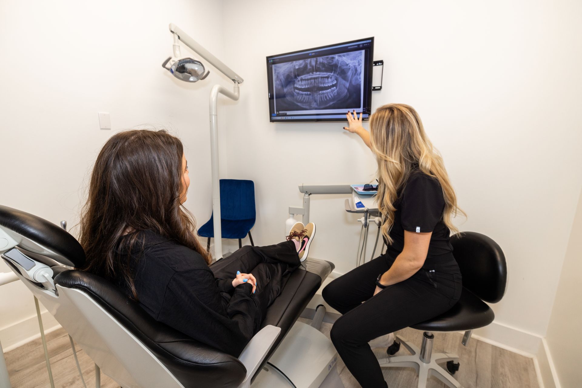 women in dental chair looking at x ray