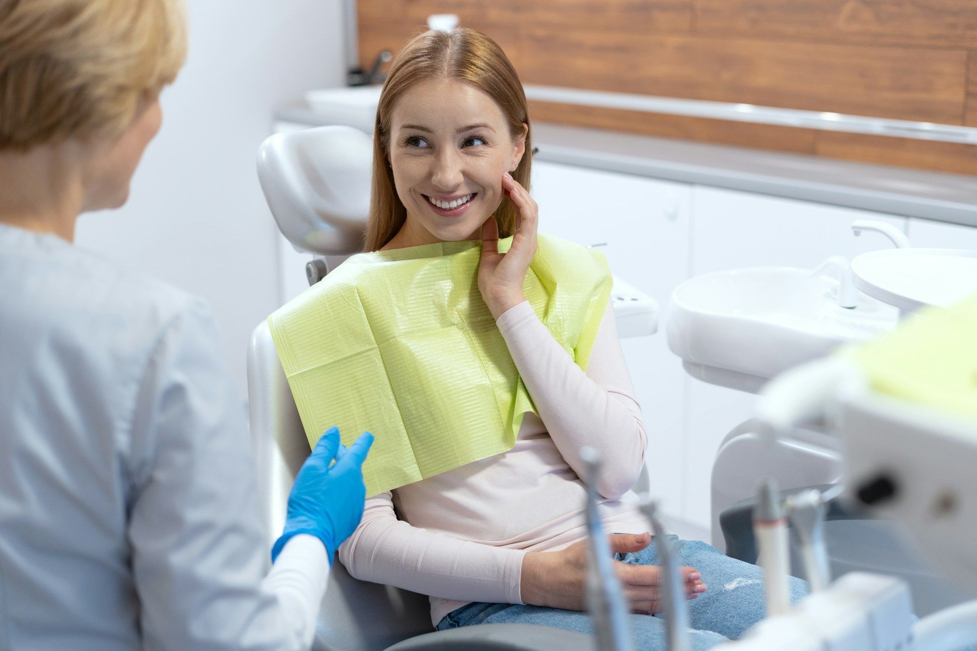 A woman is sitting in a dental chair talking to a dentist.