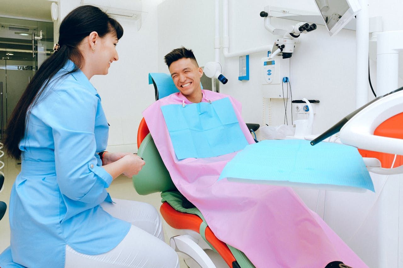 A dentist is talking to a patient in a dental chair.