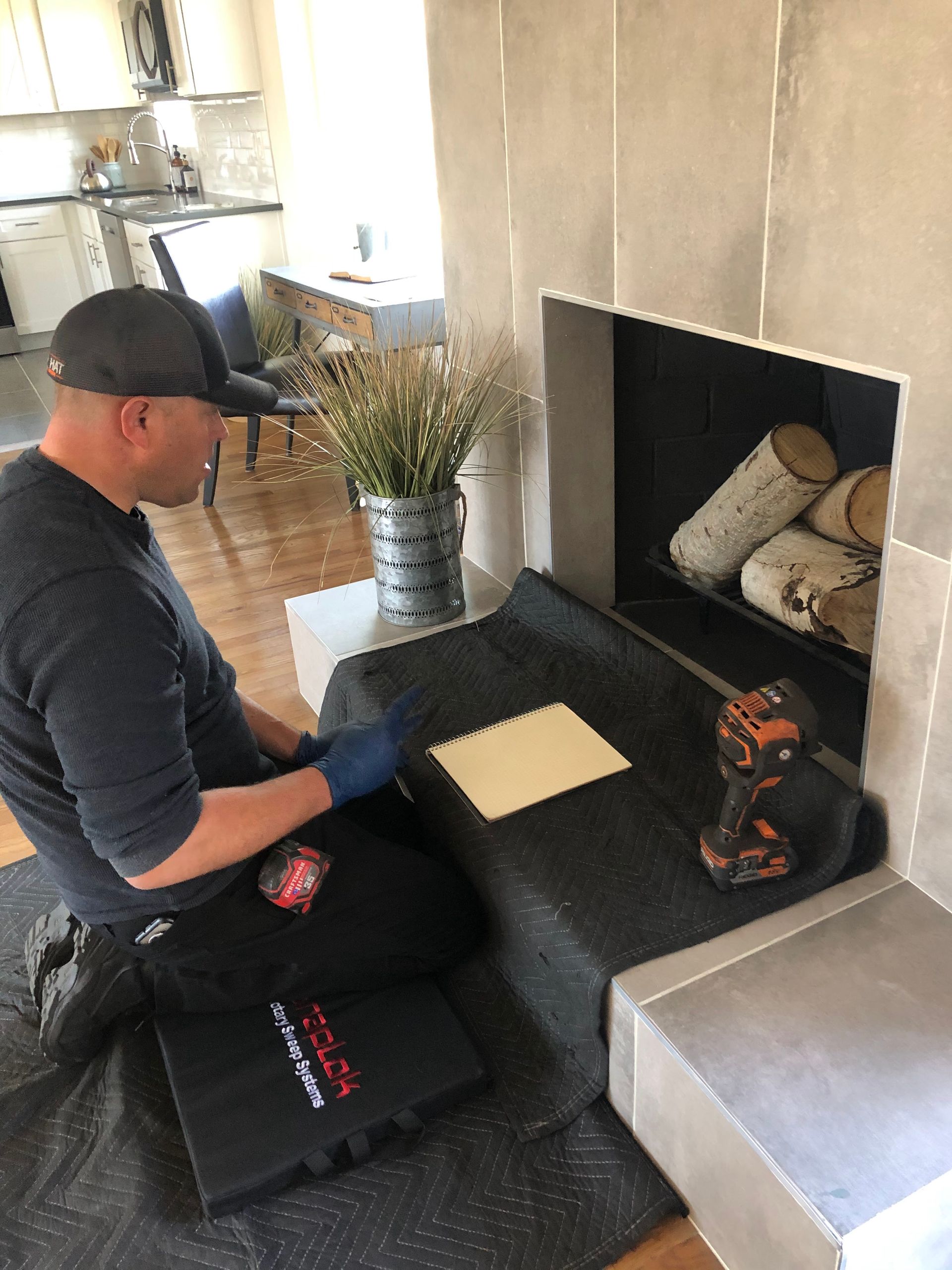 A man is sitting on the floor in front of a fireplace.