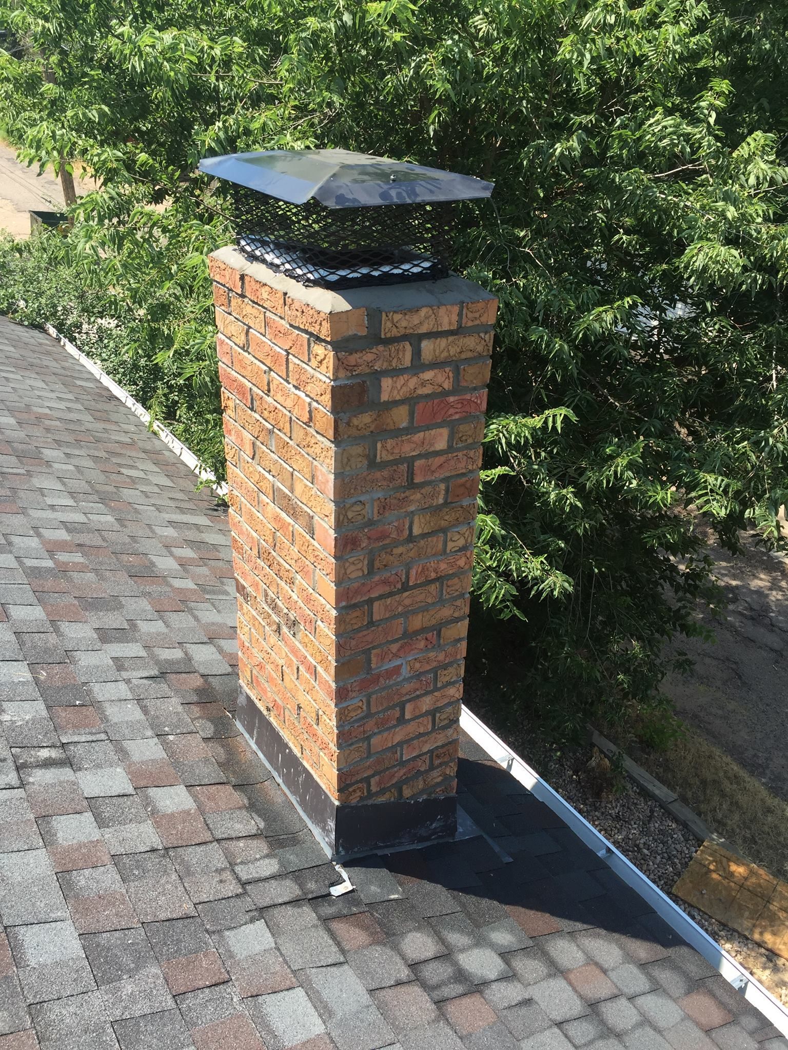 A brick chimney is sitting on top of a roof.
