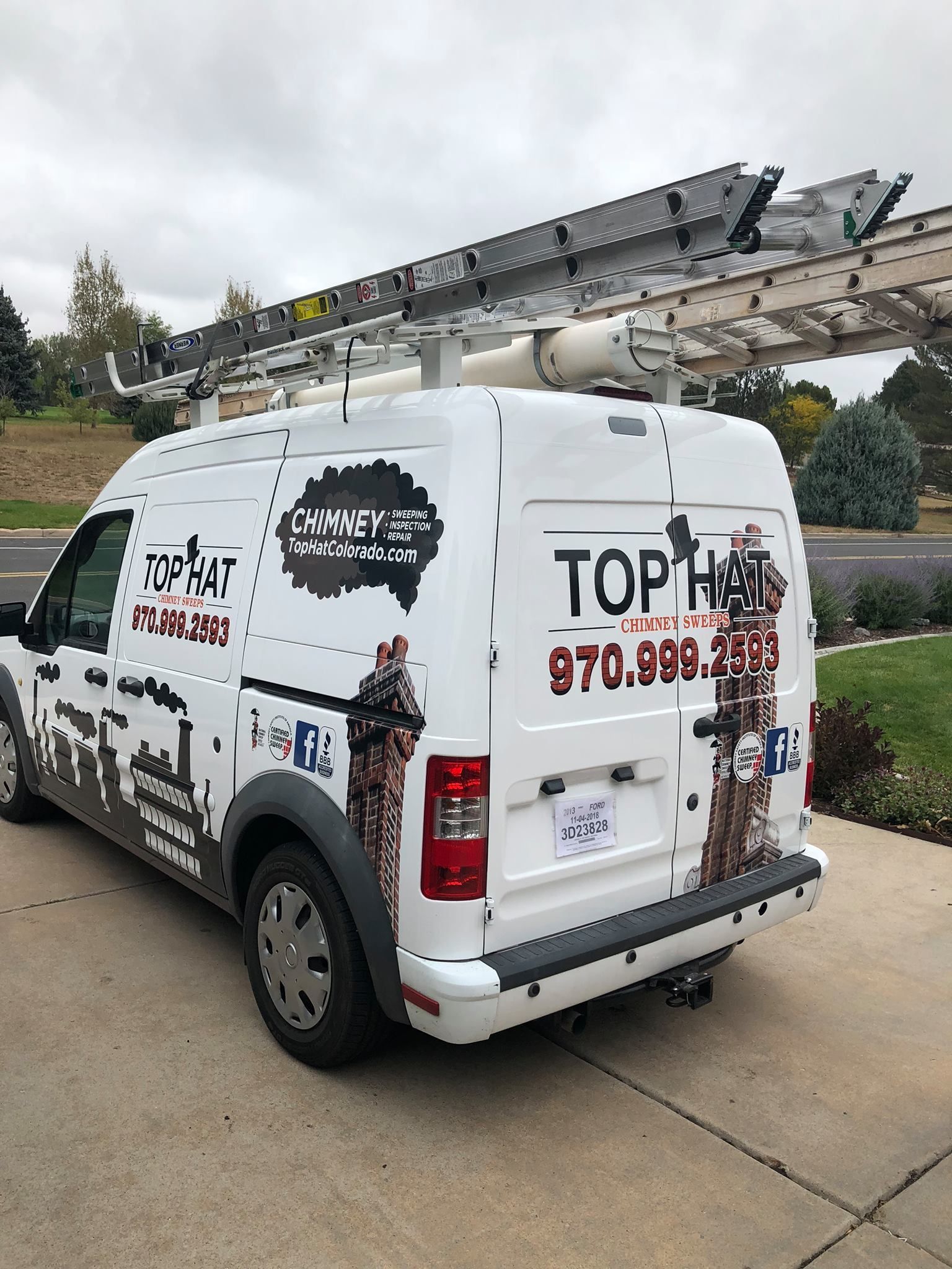 A white van with a ladder on top of it is parked on the side of the road.