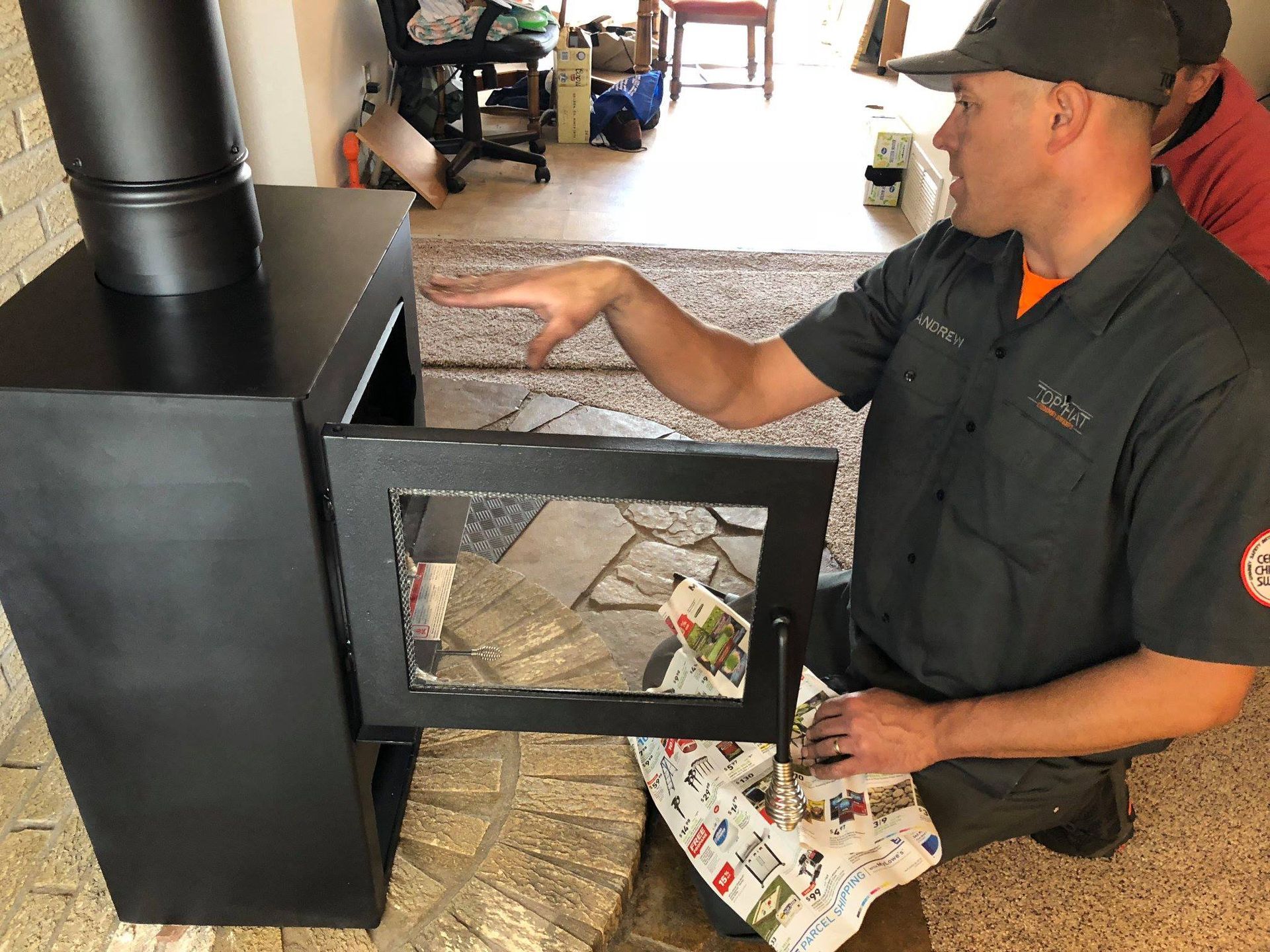 A man is kneeling down in front of a wood stove.