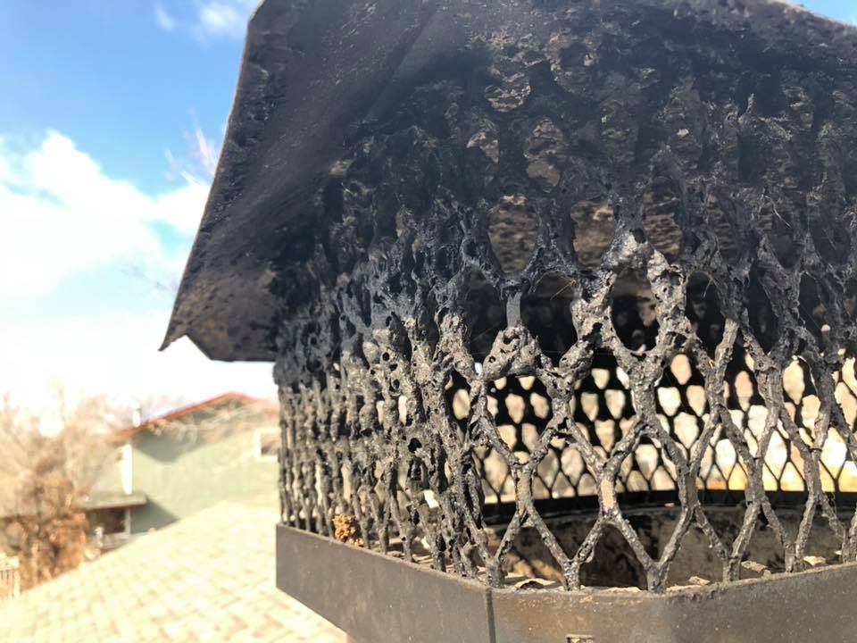A close up of a chimney with a roof in the background.