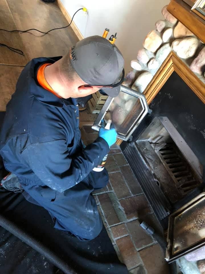 A man is cleaning a fireplace with a vacuum cleaner.
