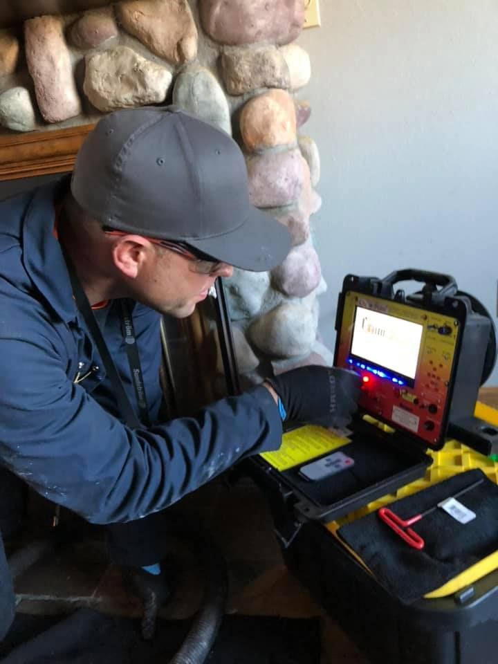 A man is sitting in front of a fireplace using a computer.