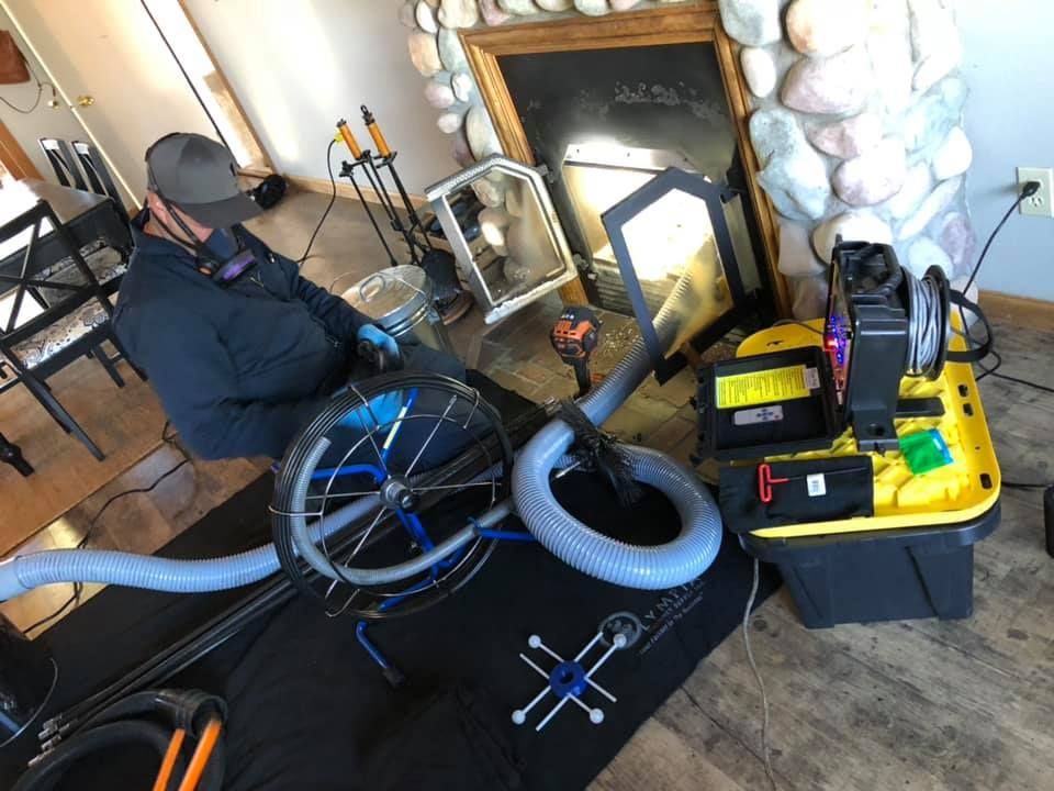 A man is sitting in a living room next to a fireplace.
