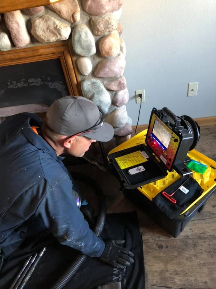 A man is kneeling down in front of a fireplace using a laptop