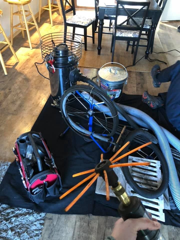 A person is sitting on the floor with a vacuum cleaner and other tools.