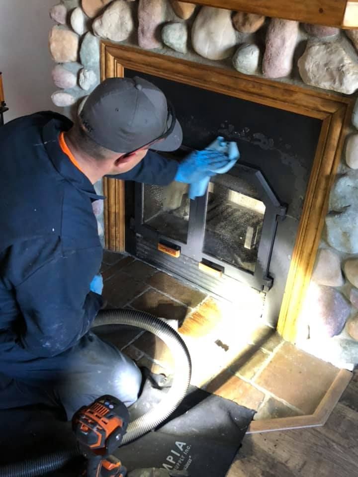A man is cleaning a fireplace with a vacuum cleaner.