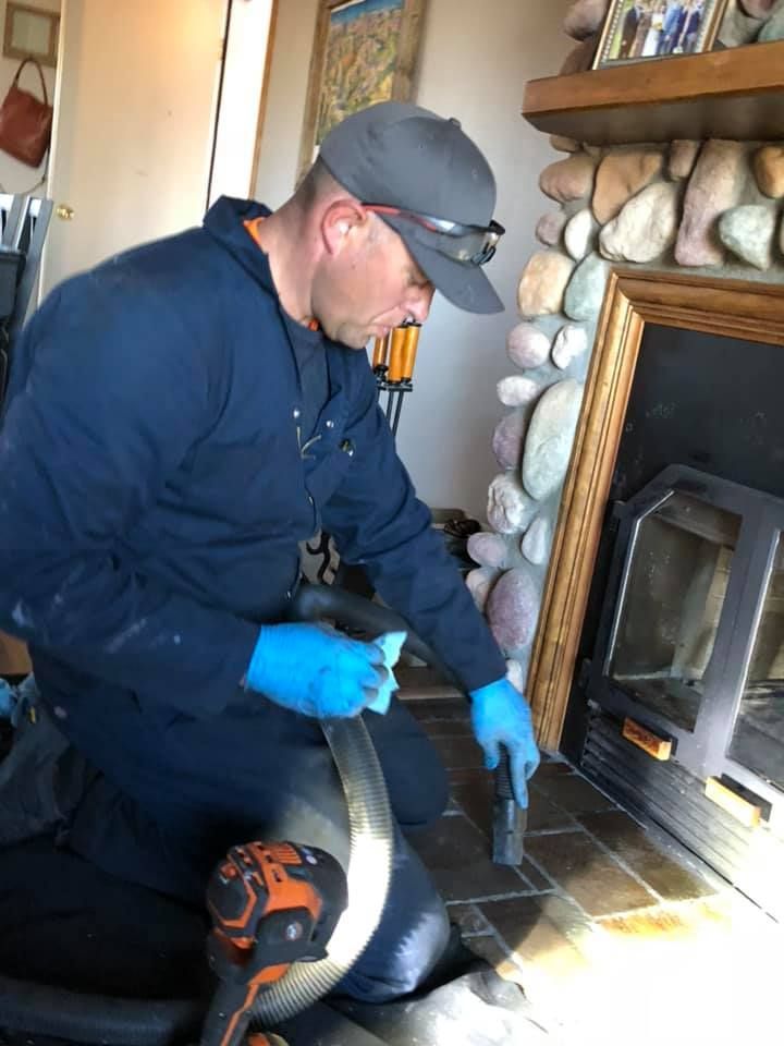 A man is cleaning a fireplace with a vacuum cleaner.