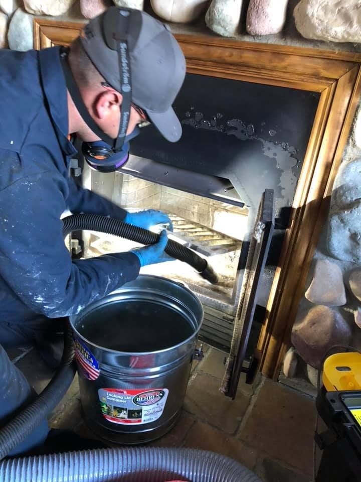A man is cleaning a fireplace with a vacuum cleaner.