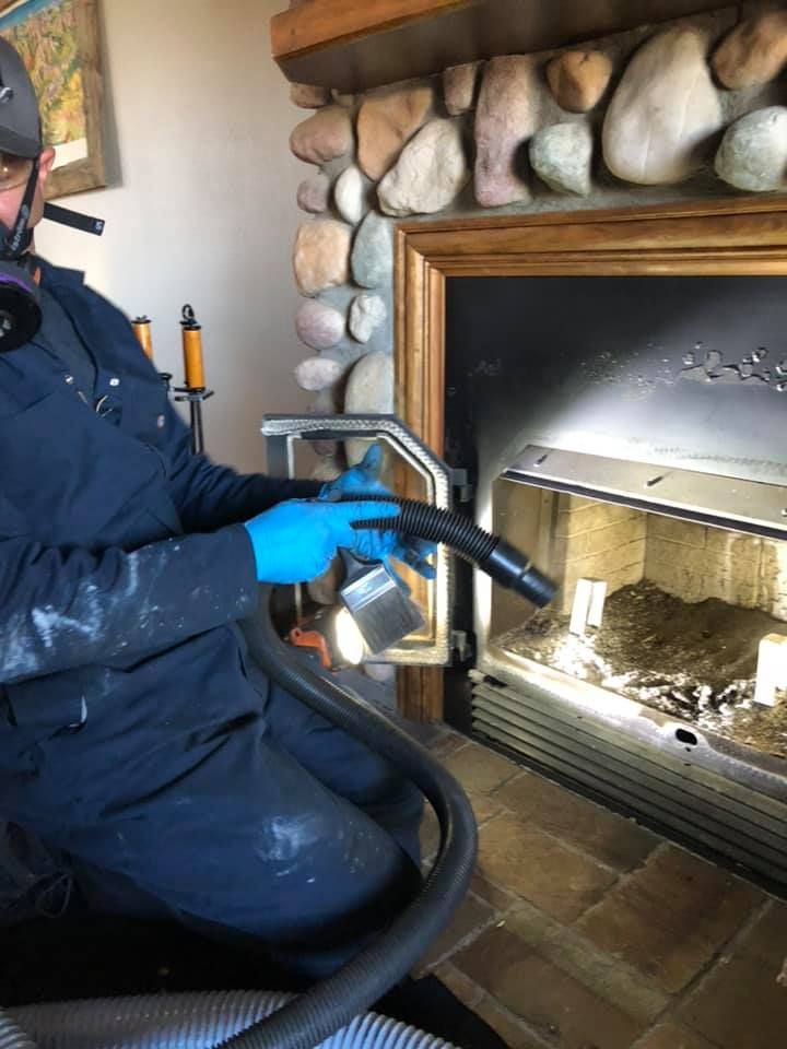 A man is cleaning a fireplace with a vacuum cleaner.