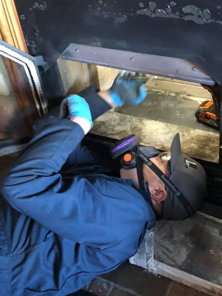 A man wearing a gas mask is working on a fireplace.
