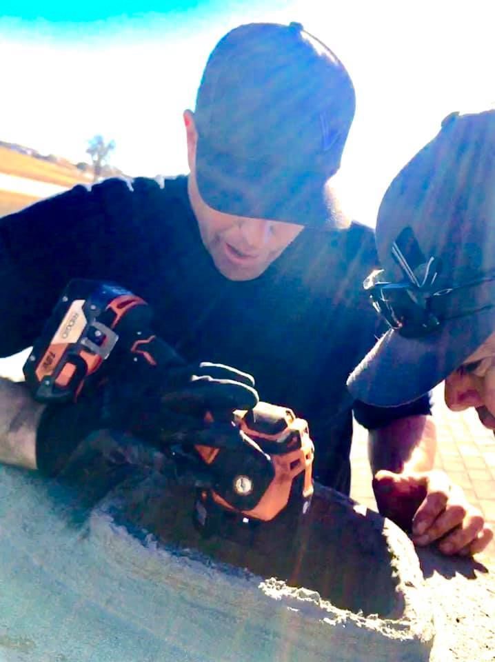 Two men wearing hats and gloves are working on a piece of concrete