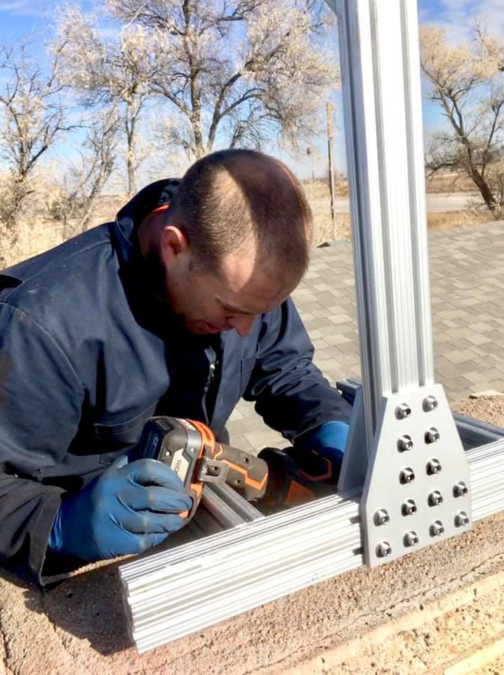 A man is working on a metal structure with a drill.