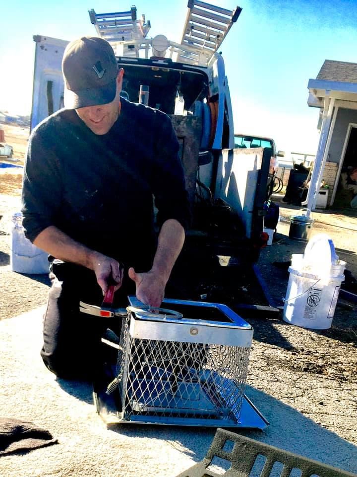 A man is working on a cage in front of a van.