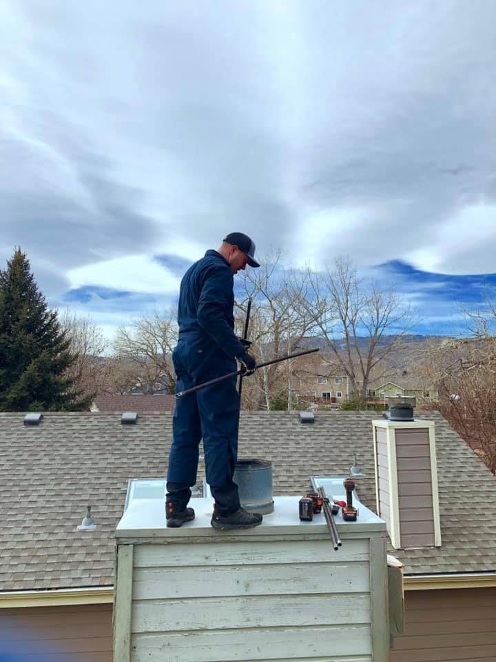 A man is standing on top of a chimney on a roof.