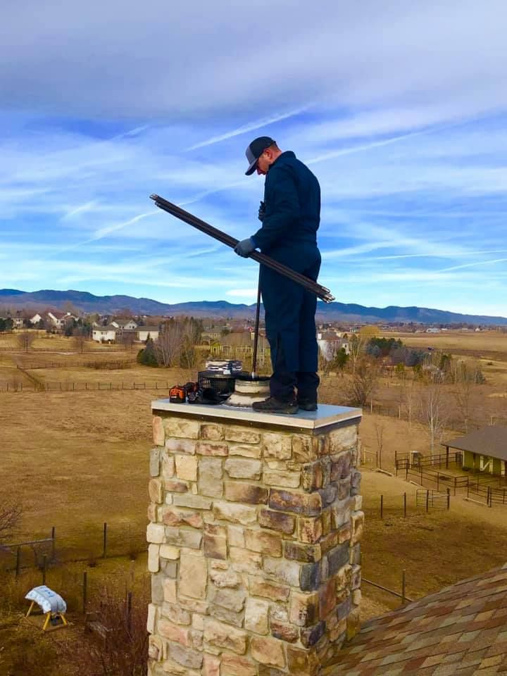 A man is standing on top of a stone chimney.