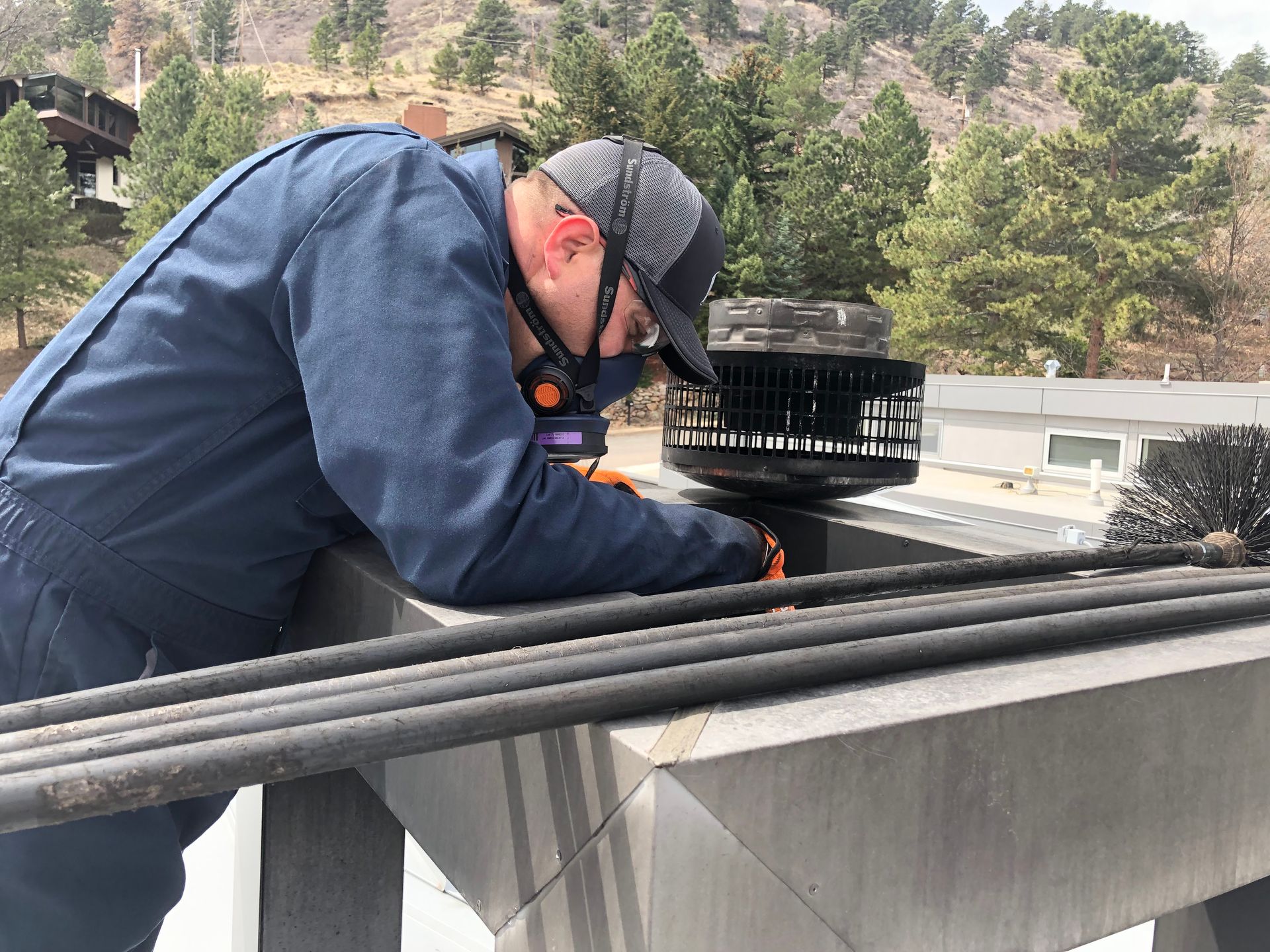A man is working on a chimney on top of a building.