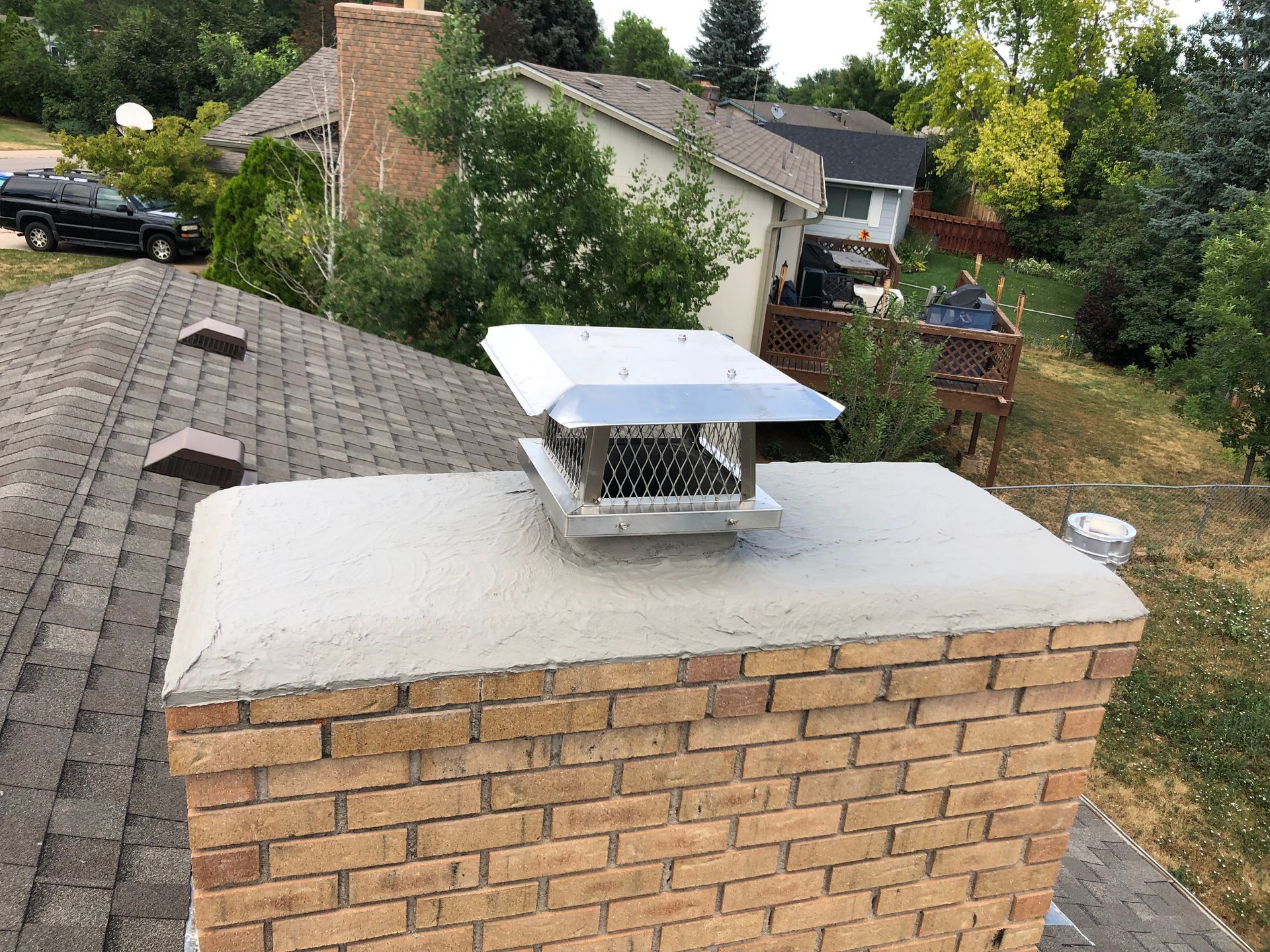 A brick chimney on top of a roof next to a house.