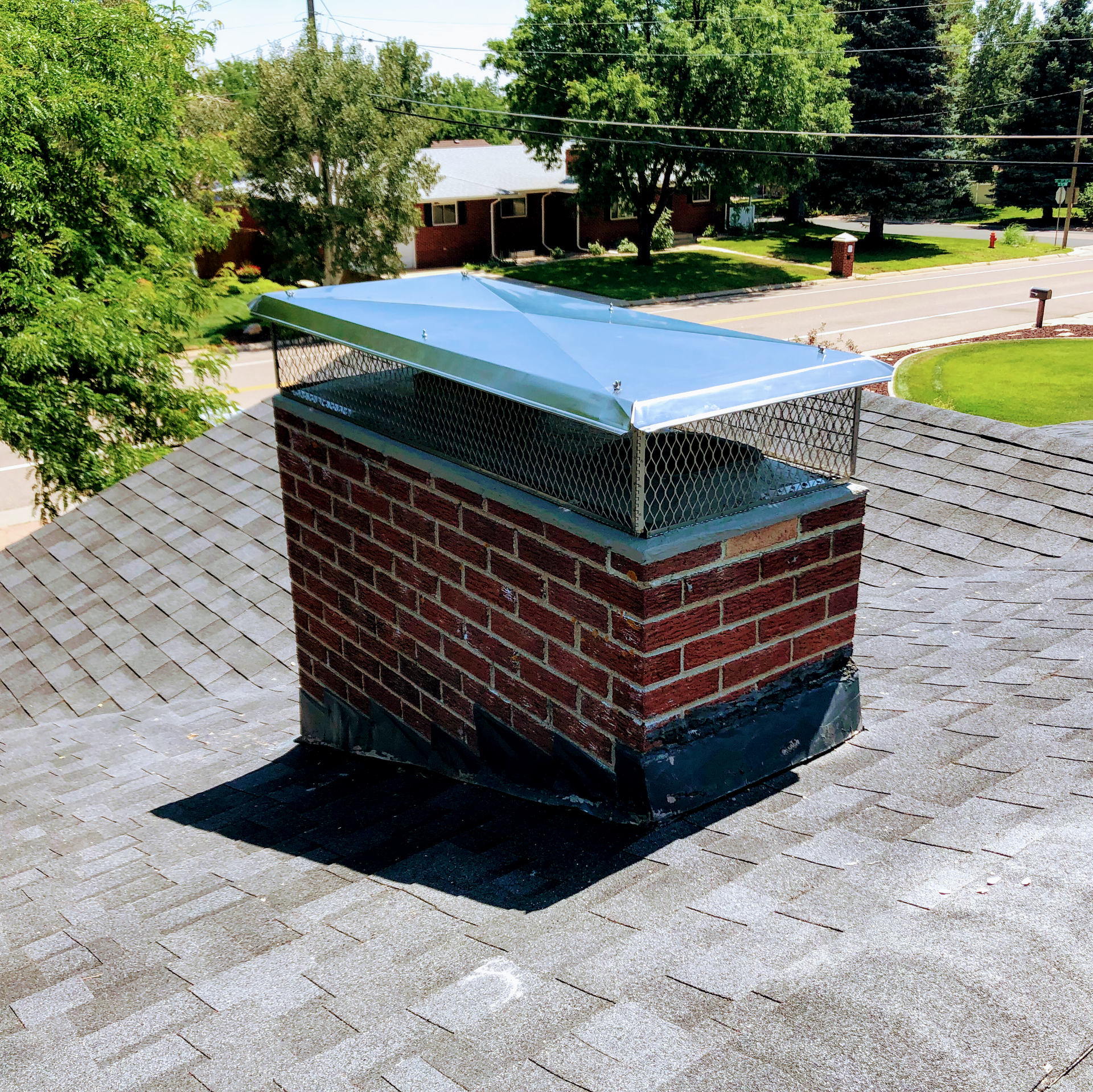 A brick chimney with a metal cover on top of it