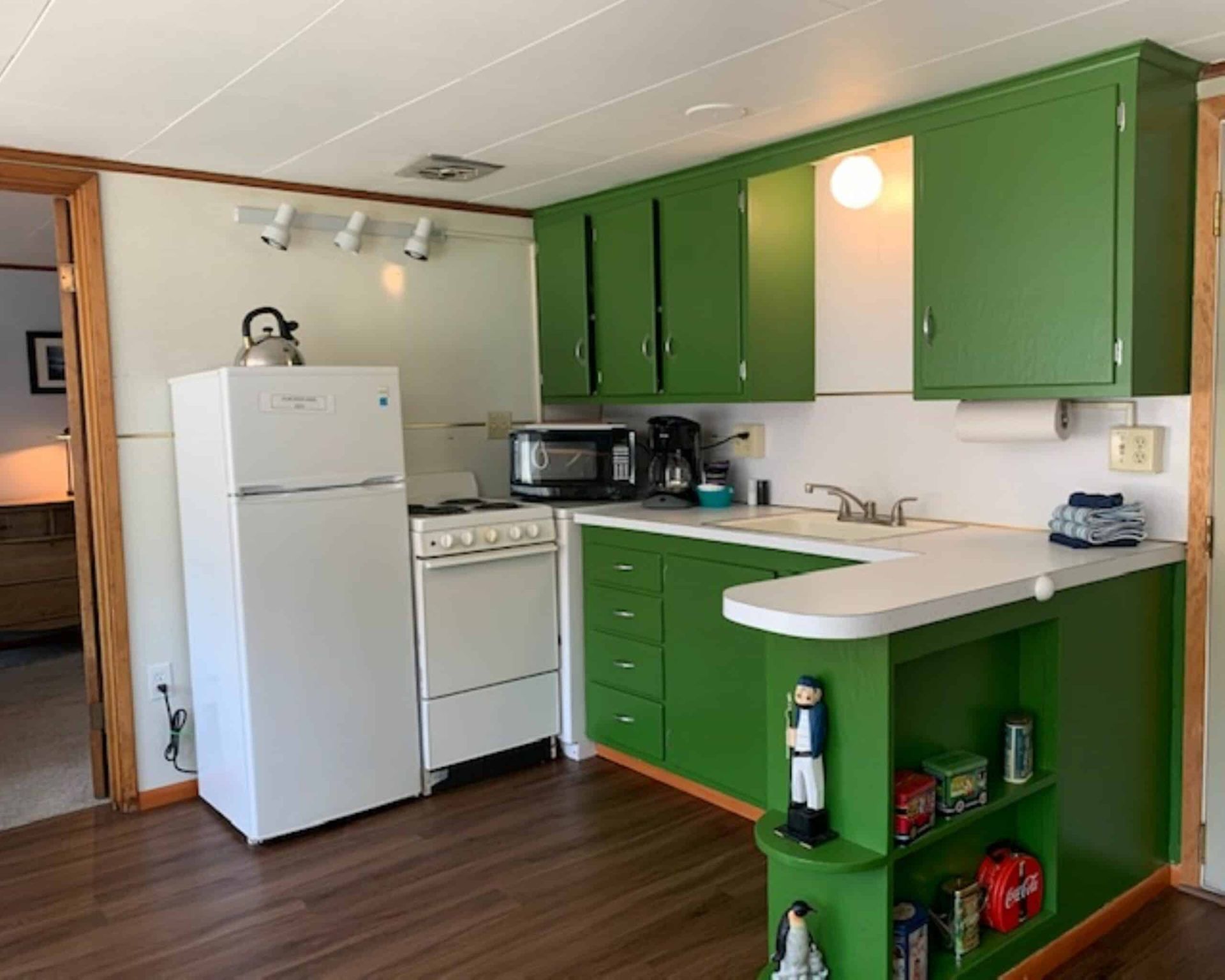 A kitchen with green cabinets and a white refrigerator.