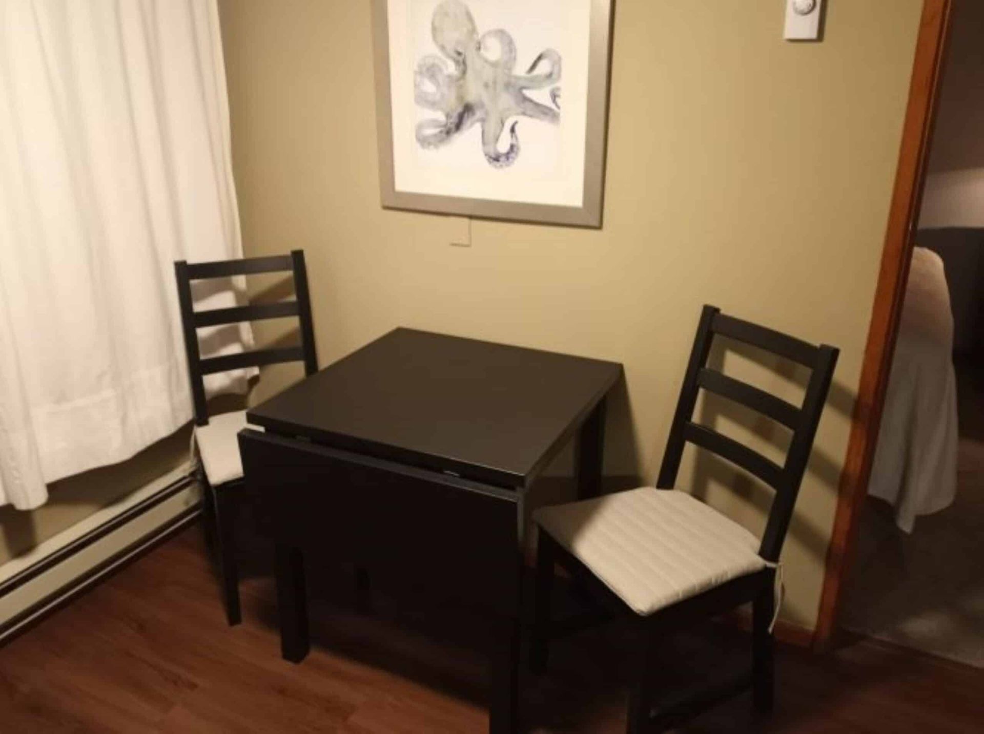 Two chairs and a table in a room with a picture of an octopus on the wall