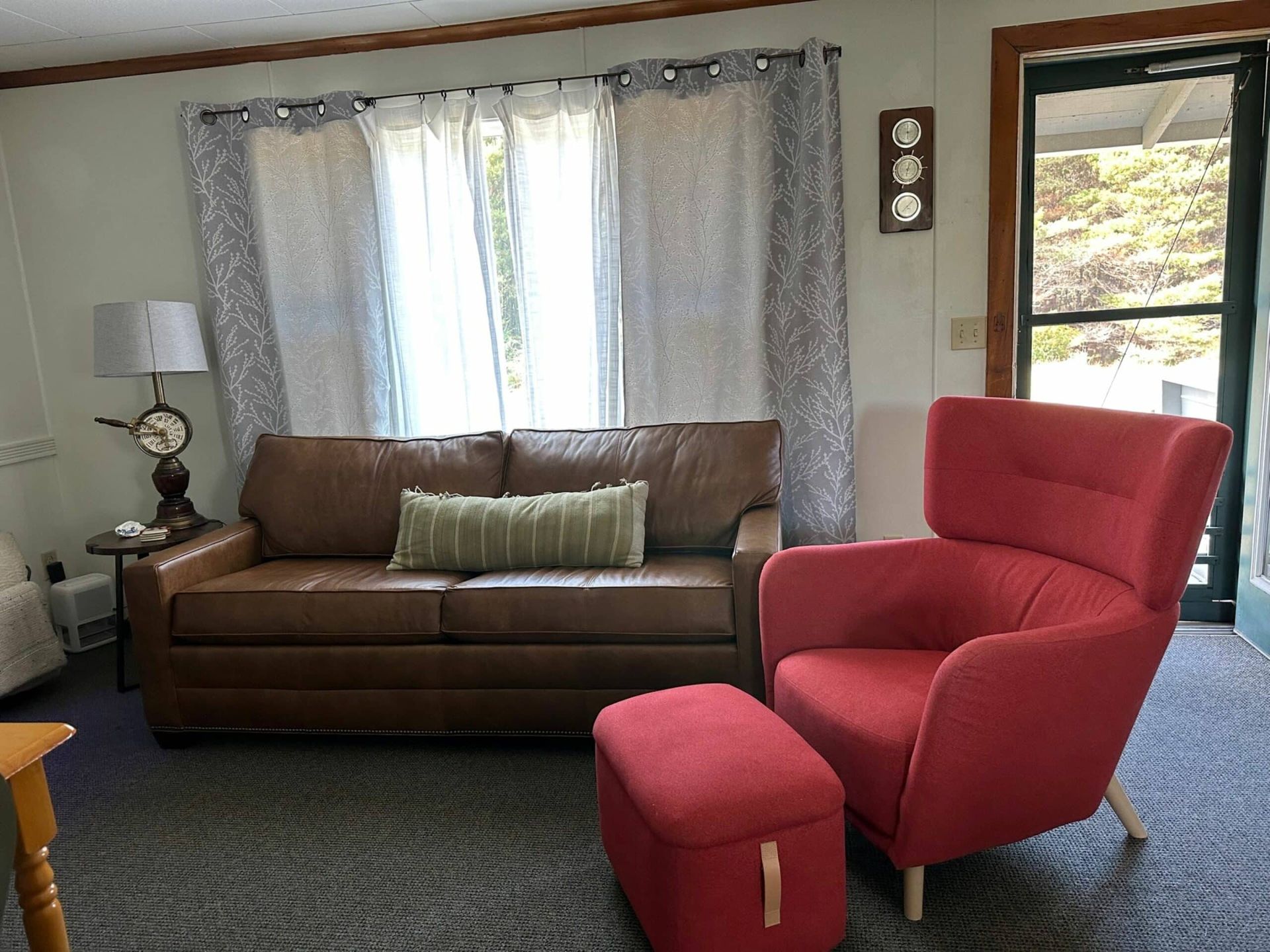 A living room with a brown couch and a red chair