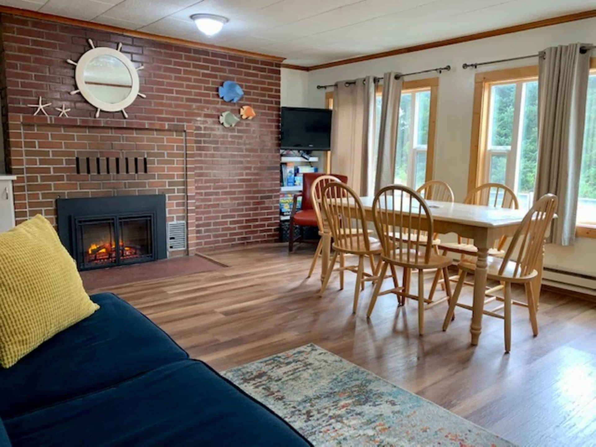 A living room with a couch , table and chairs and a fireplace.