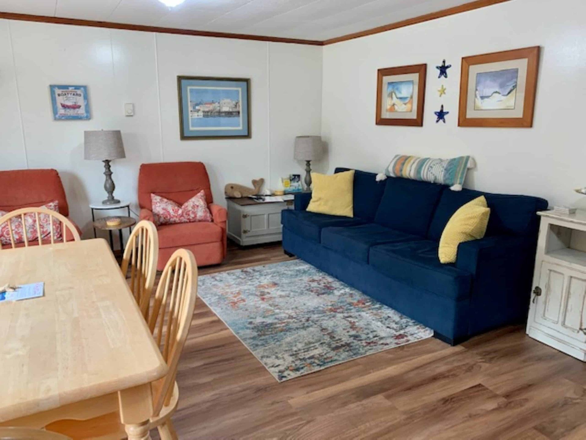 A living room with a blue couch , two chairs , a table and a rug.