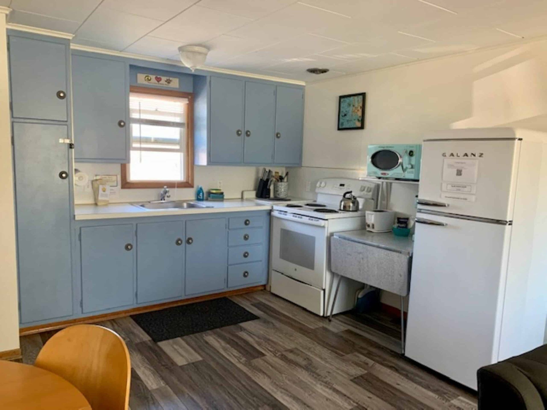 A kitchen with blue cabinets , a white refrigerator , a stove , and a microwave.