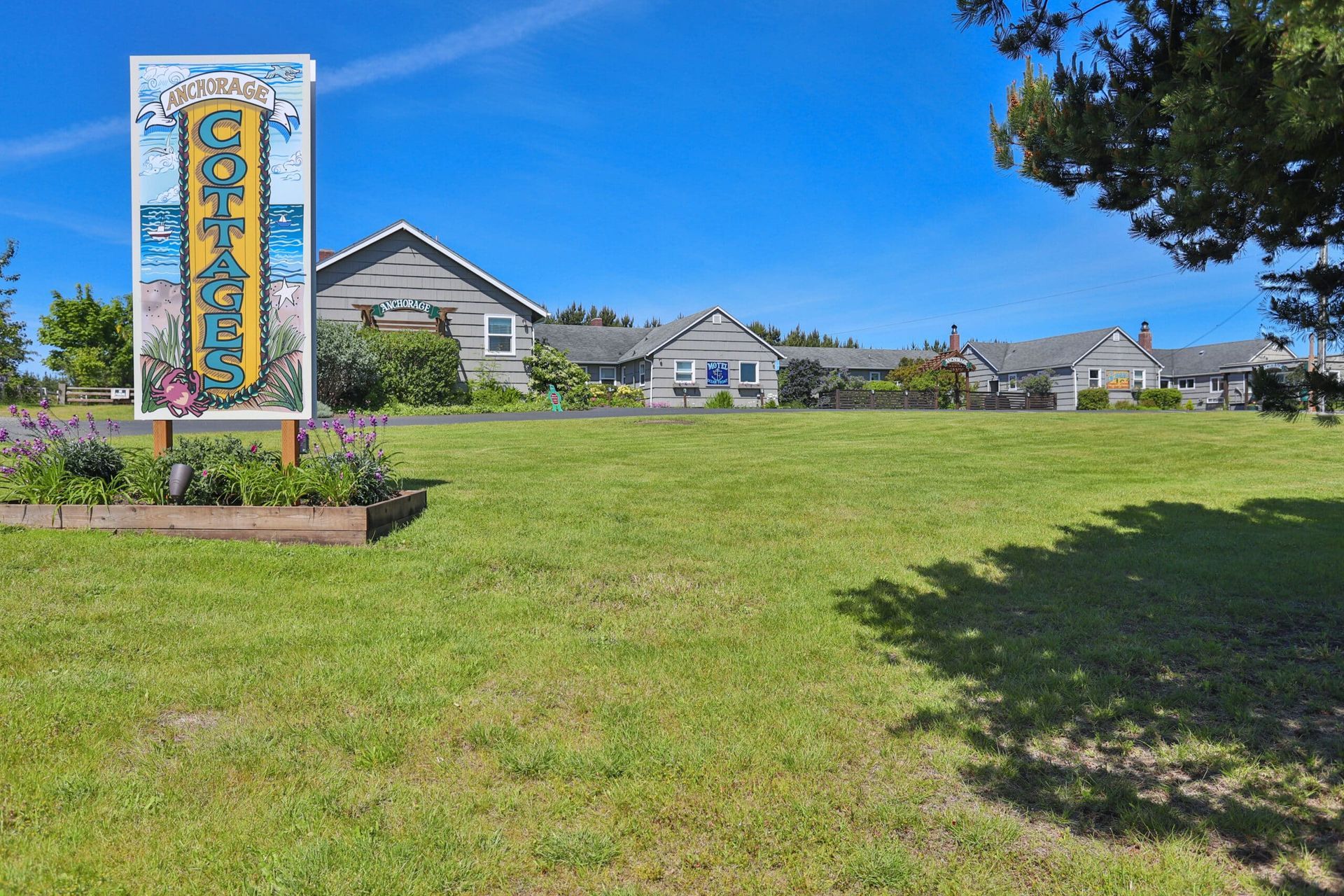 A large sign in the middle of a grassy field with houses in the background.