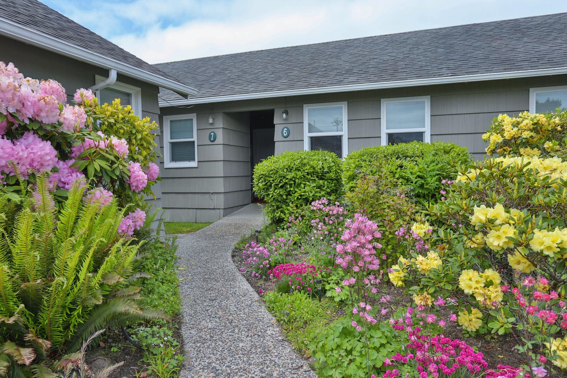 A house with flowers in front of it and a walkway leading to it.
