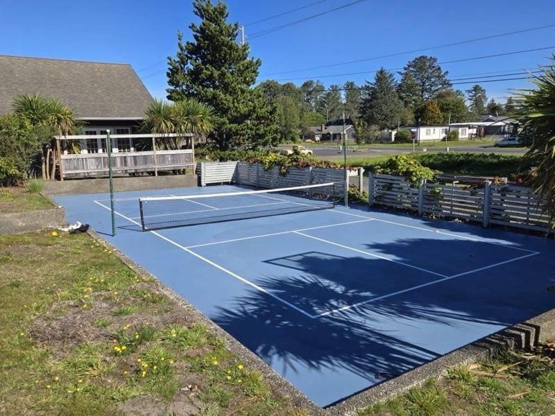 A tennis court in front of a house on a sunny day