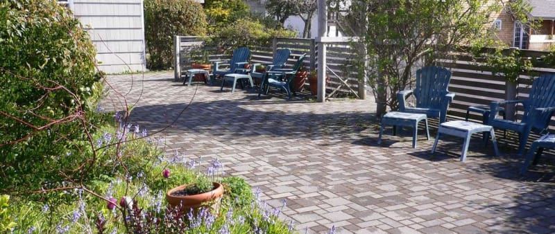 A patio with blue chairs and a potted plant