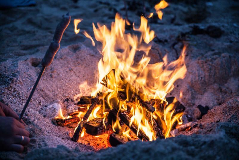 A person is roasting marshmallows over a campfire on the beach.