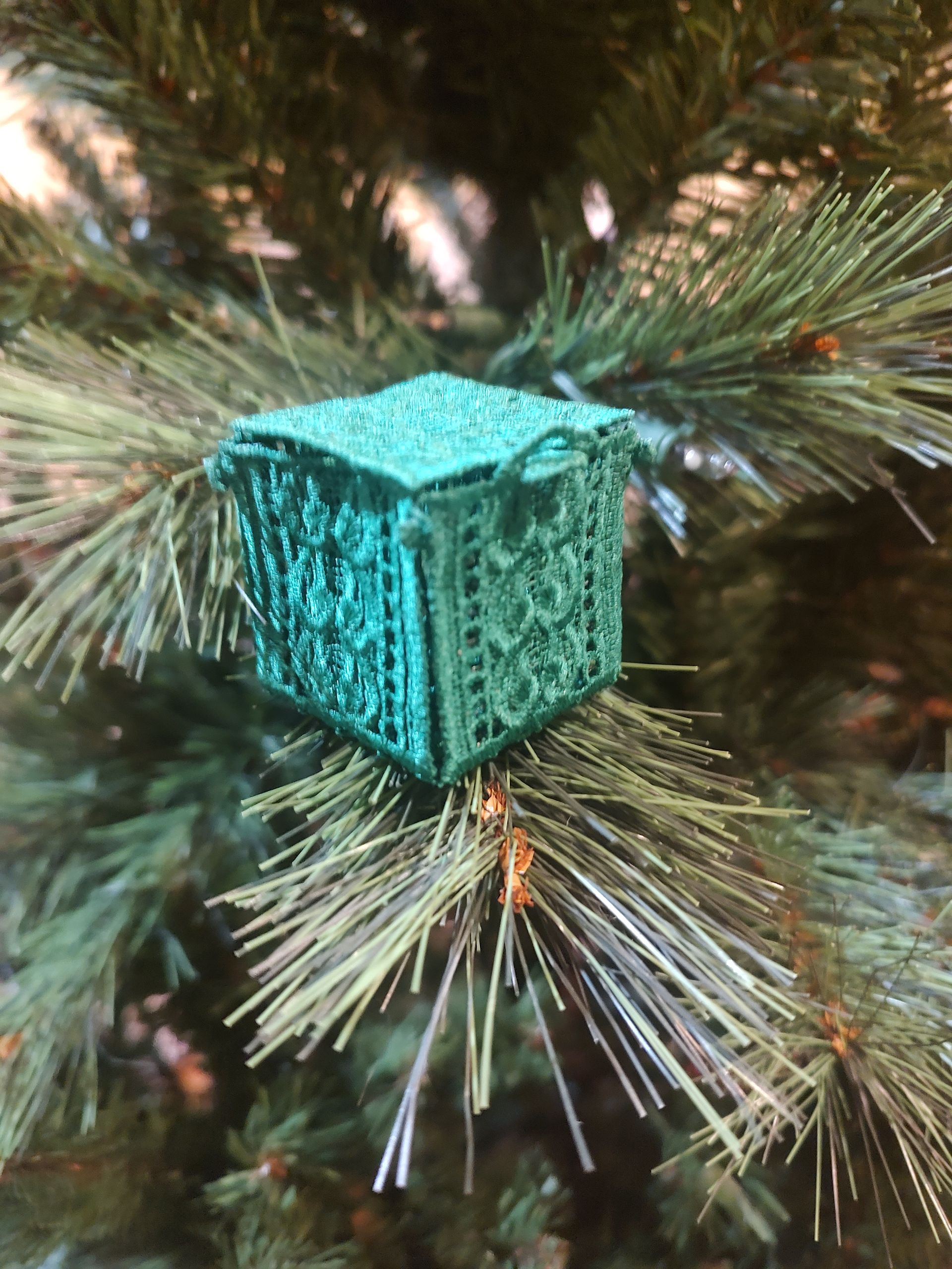 Green, ornate, open, miniature chest ornament on Christmas tree.
